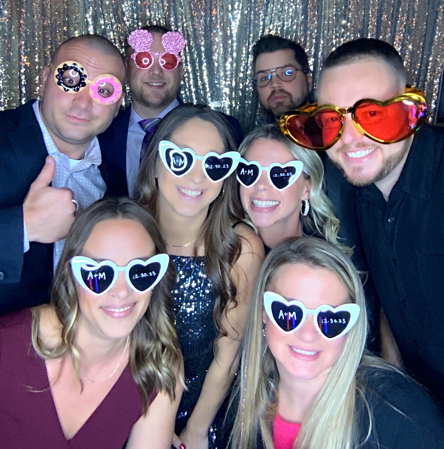 Wedding guests having fun with heart-shaped glasses and photo booth props